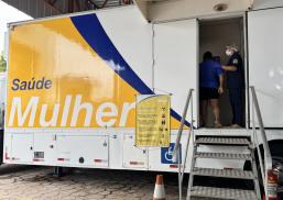Há um treiler escrito Saúde da Mulher. Ele está com uma porta aberta, uma enfermeira recebendo uma mulher